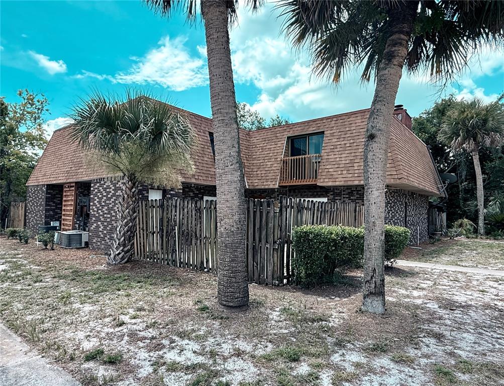 A two-story brick building with a mansard roof, a wooden fence, and palm trees — 202 TERRACE COURT, SANFORD, FL