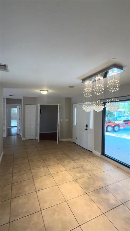 A tiled entryway features a modern chandelier, a white front door, and an open doorway — 3109 RESEDA COURT, TAMPA, FL