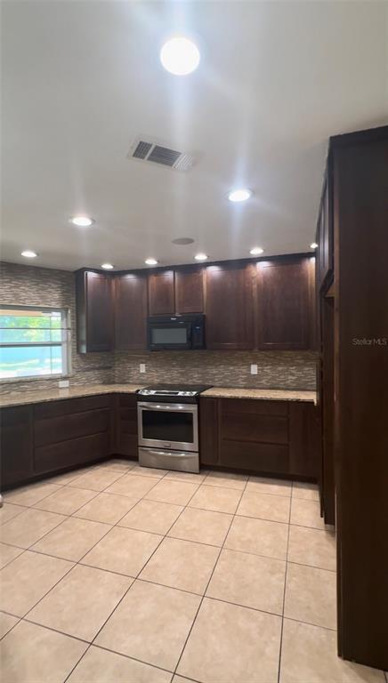 A kitchen features dark wood cabinets, stainless steel appliances, granite countertops, and tiled flooring — 3109 RESEDA COURT, TAMPA, FL