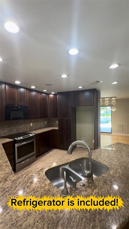 A kitchen features dark wood cabinets, granite countertops, a stainless steel stove, and a sink — 3109 RESEDA COURT, TAMPA, FL