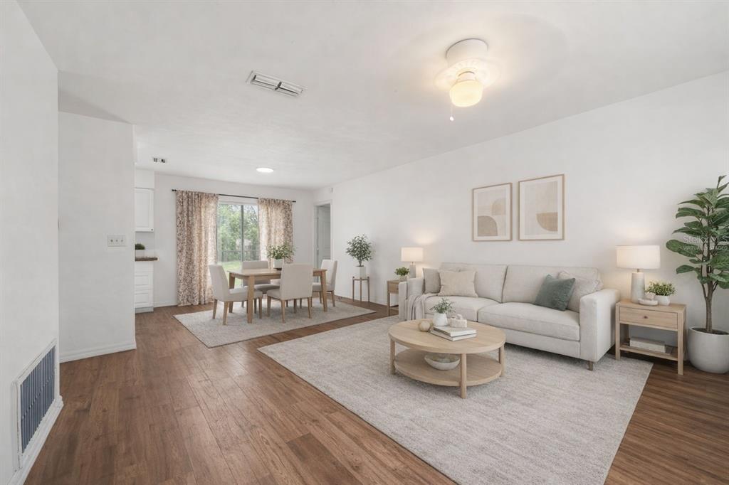 This virtually staged living and dining area features white walls, wood-look flooring, and neutral furniture — 1911 SE 14TH AVENUE, GAINESVILLE, FL