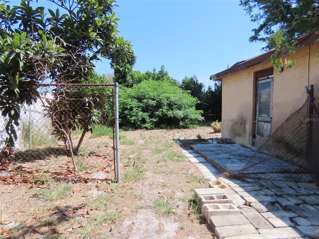 A view of a backyard with a chain-link fence, a paved patio, and a building — 3911 W LEILA AVENUE, TAMPA, FL