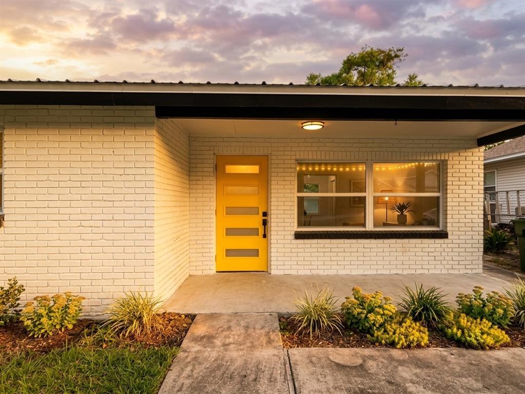 A white brick house exterior features a bright yellow front door and a covered porch — 139 AVENUE D SW, WINTER HAVEN, FL