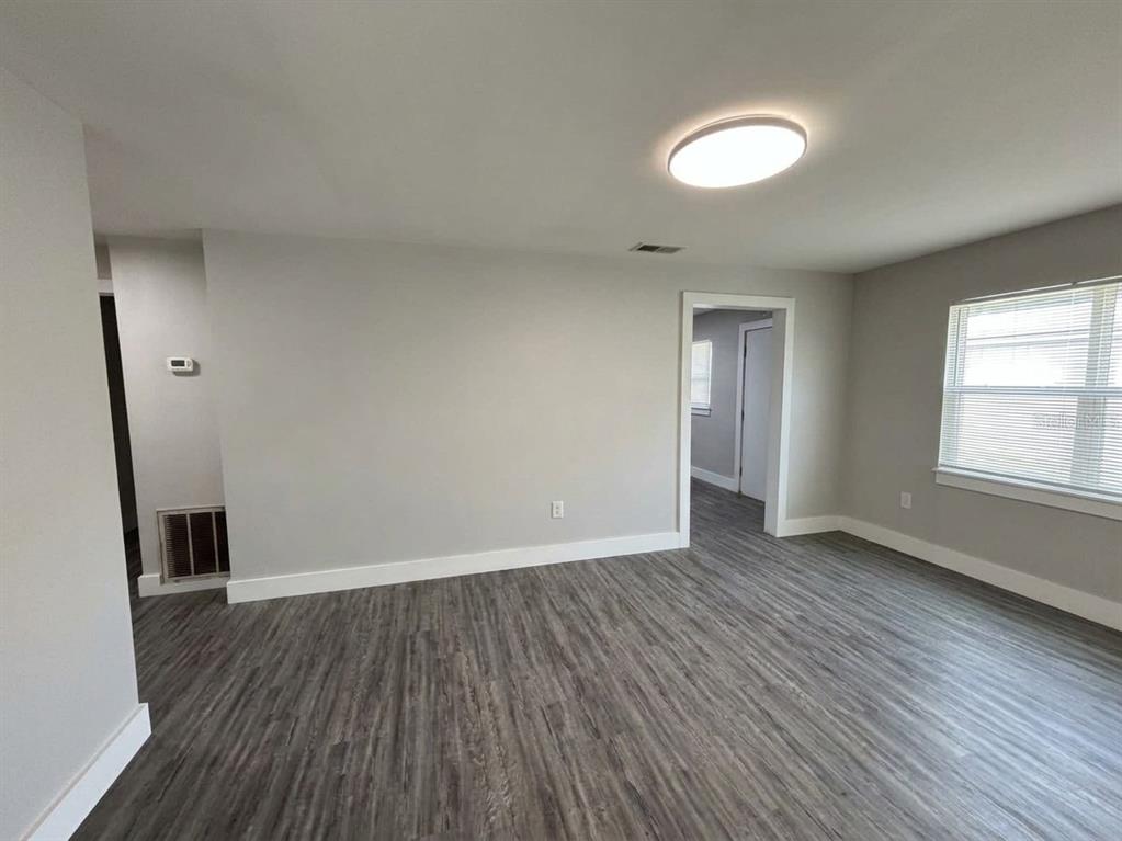An empty room features gray walls, wood-look flooring, a ceiling light, and a window — 139 AVENUE D SW, WINTER HAVEN, FL
