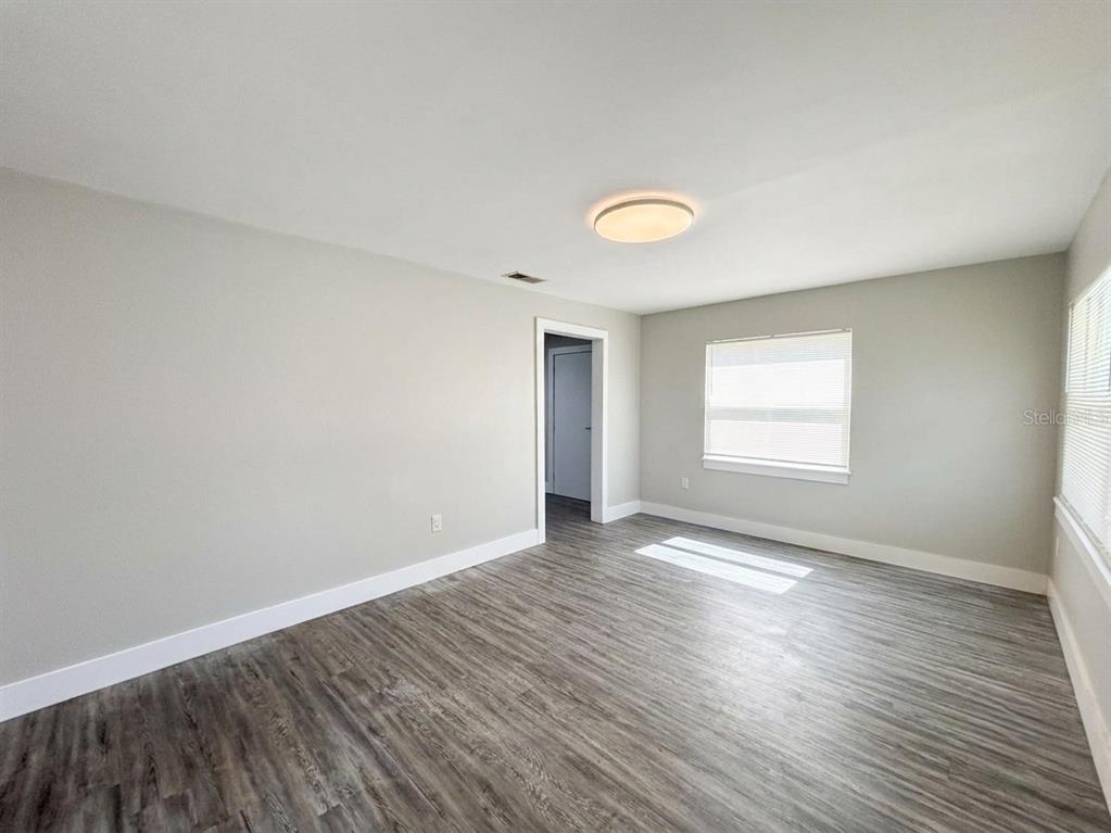 An empty room with light gray walls, wood-look flooring, a ceiling light, and two windows — 139 AVENUE D SW, WINTER HAVEN, FL