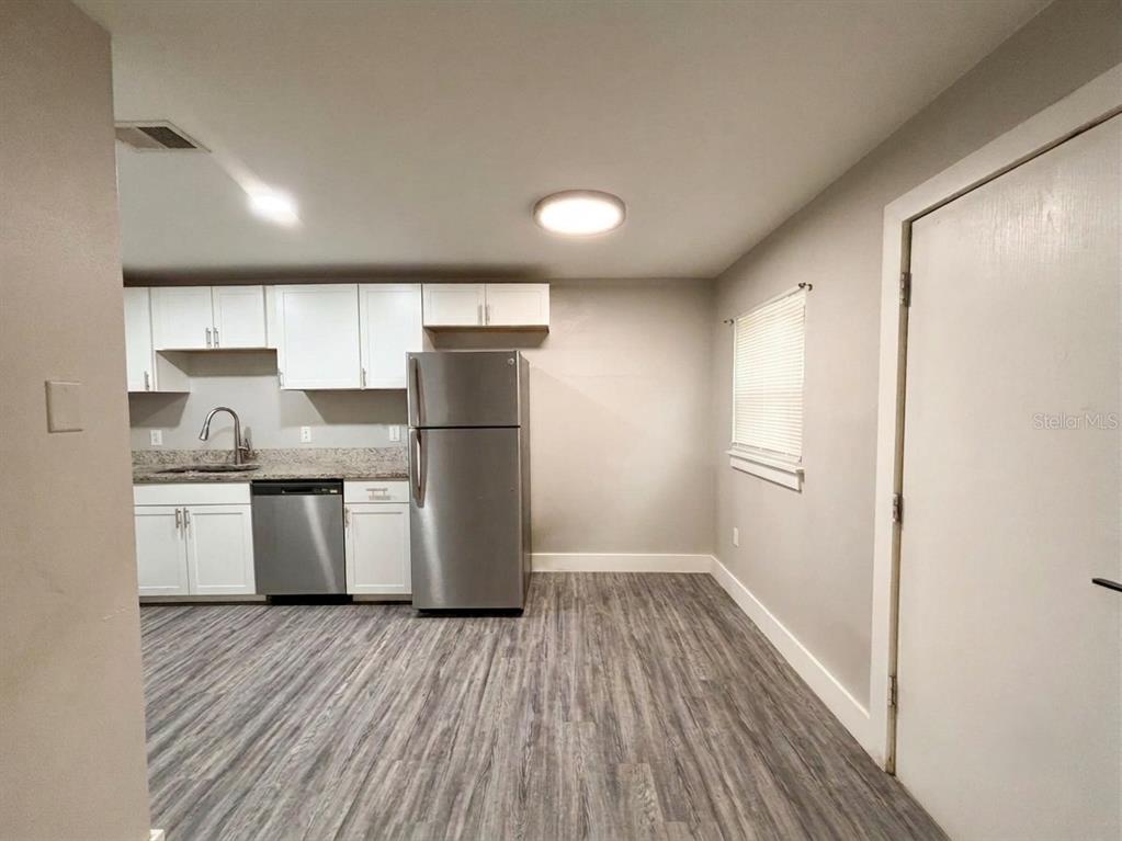 A kitchen features white cabinets, stainless steel appliances, granite countertops, and wood-look flooring — 139 AVENUE D SW, WINTER HAVEN, FL