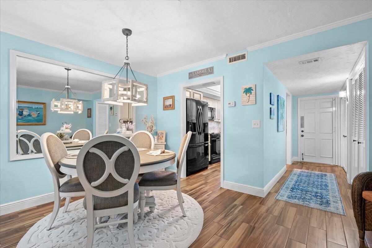A dining area with a round table and light blue walls leads into a kitchen — 1205 Sandy Lane # 145, Singer Island FL 33404, SINGER ISLAND, FL