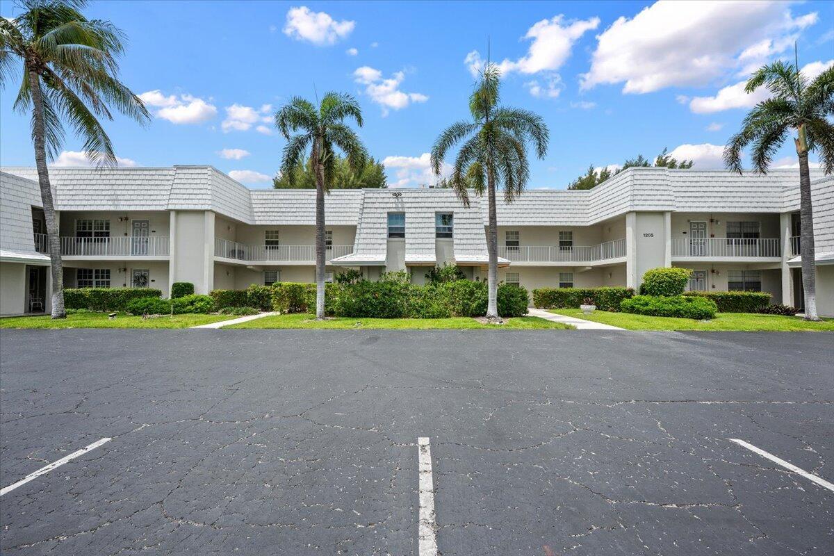 A two-story apartment building with a parking lot and palm trees in front — 1205 Sandy Lane # 145, Singer Island FL 33404, SINGER ISLAND, FL