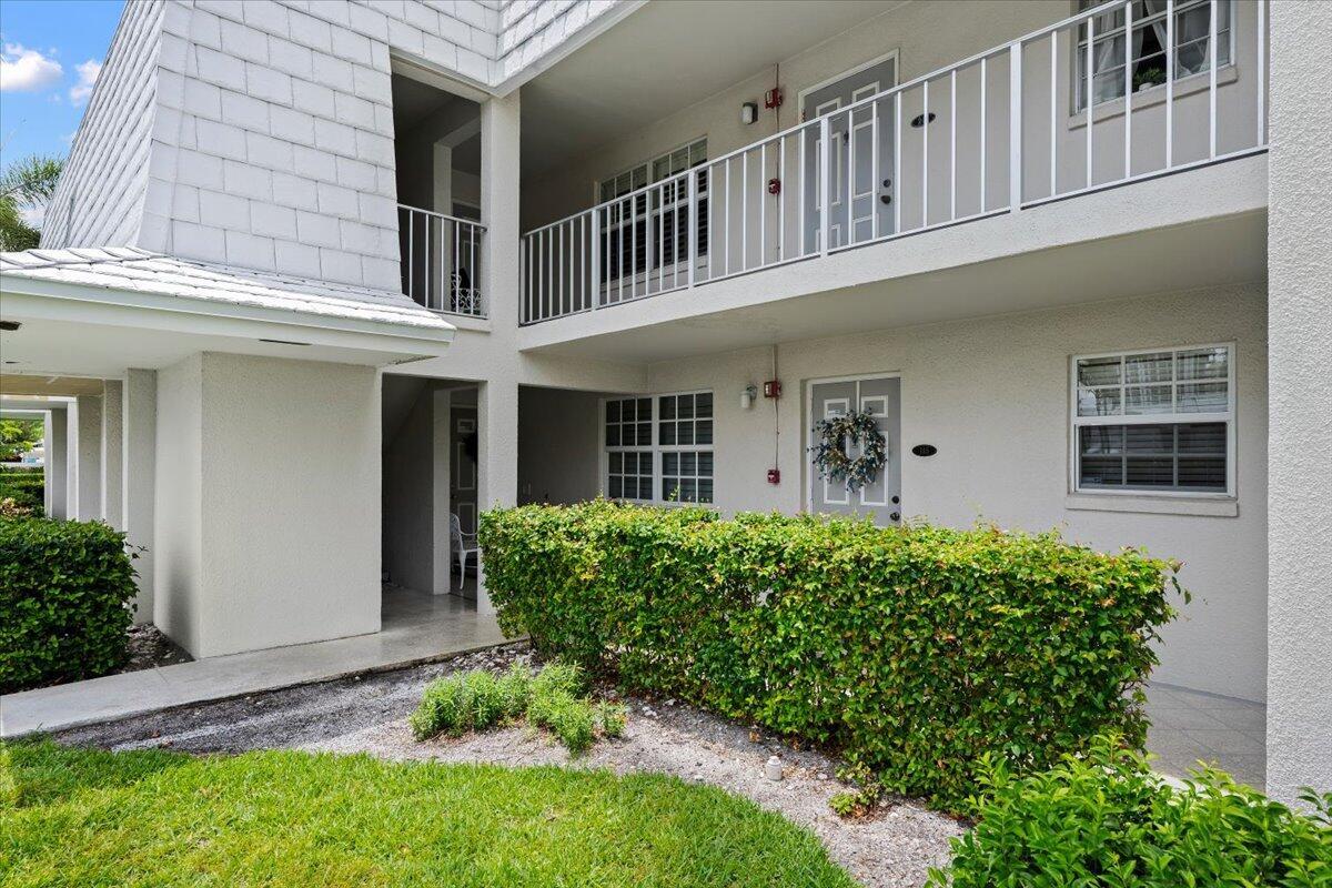A two-story apartment building exterior features a ground-level entrance with a hedge and walkway — 1205 Sandy Lane # 145, Singer Island FL 33404, SINGER ISLAND, FL