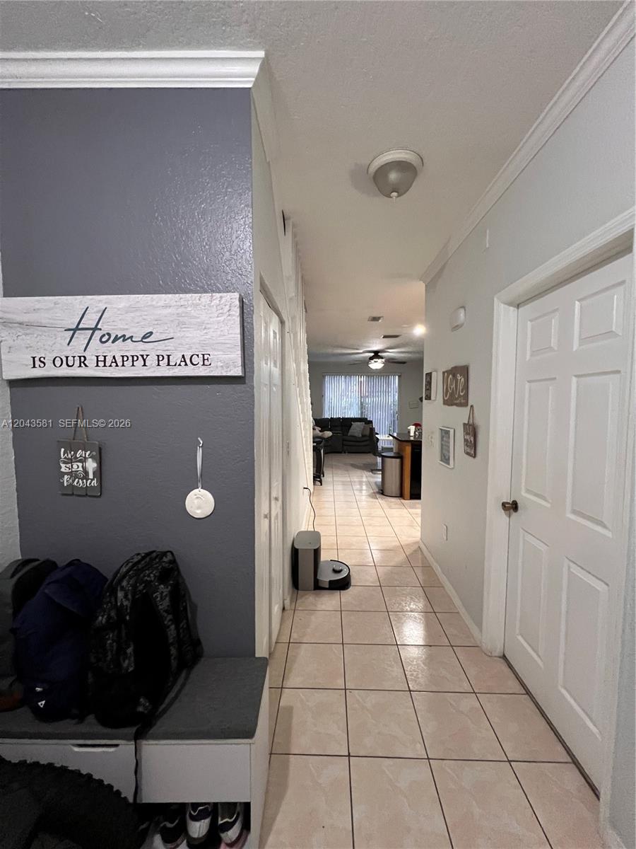 A tiled hallway leads from an entryway with a bench toward a living area — TAMARAC, FL