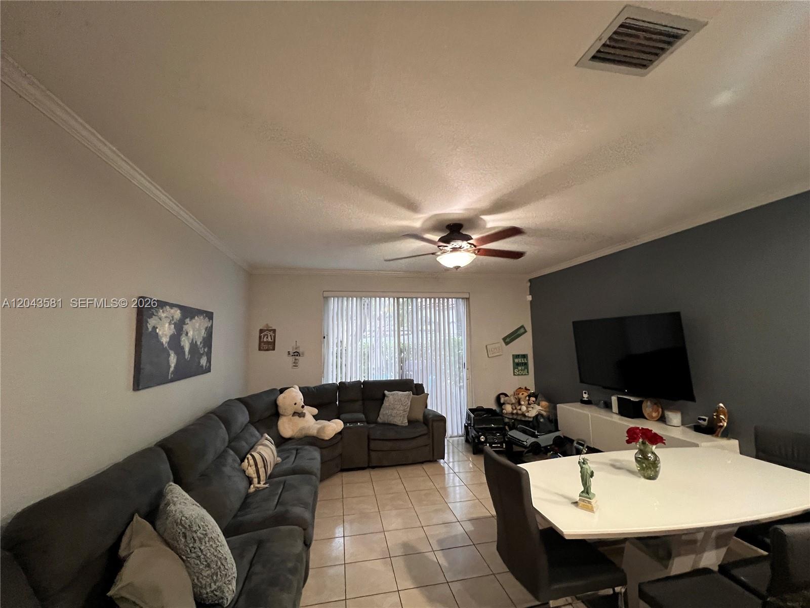 A living and dining area features a large sectional sofa, tile flooring, and a television — TAMARAC, FL