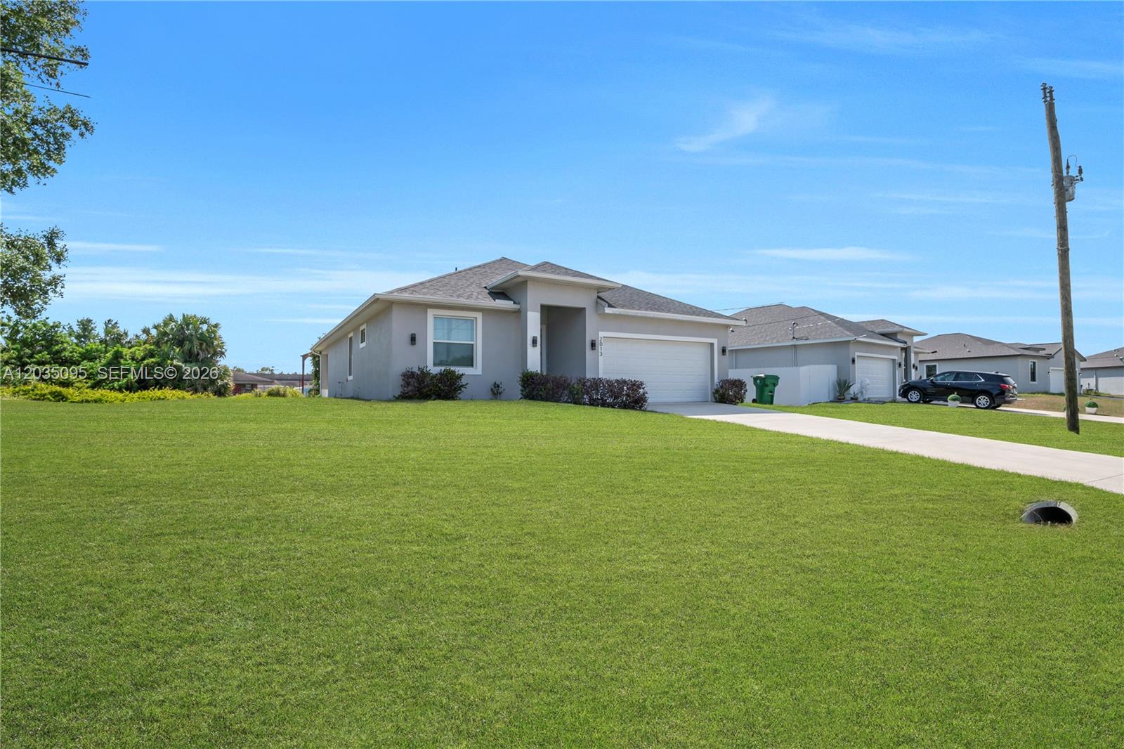 A single-story gray house with a two-car garage sits on a large, grassy lot — 2013 Inglewood, La Belle FL 33935, LA BELLE, FL