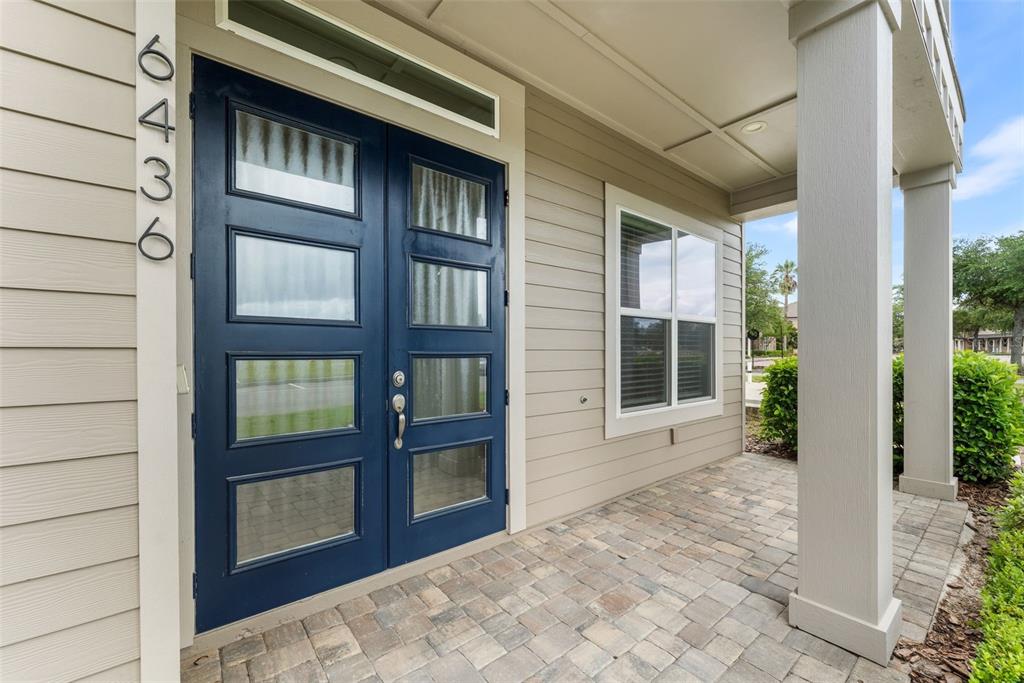 A blue double front door with glass panels sits on a paved porch with columns — 6436 SW 77TH STREET, GAINESVILLE, FL