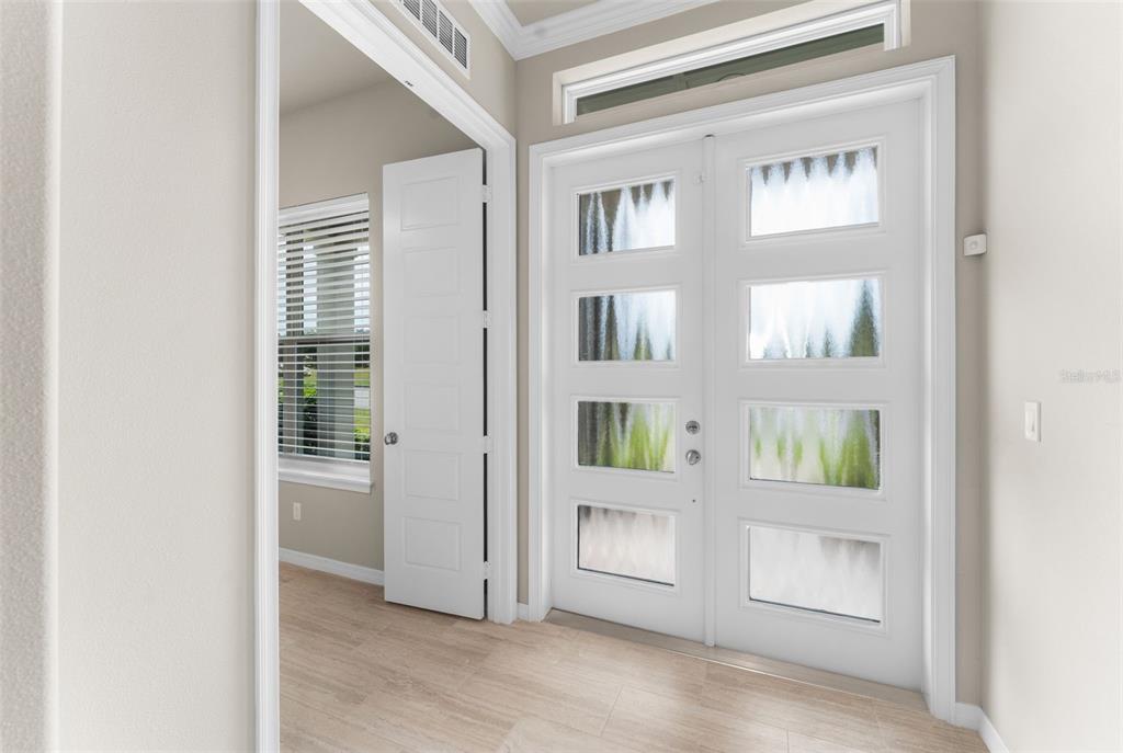 An entryway features light wood-look flooring, a white double front door, and an adjacent room — 6436 SW 77TH STREET, GAINESVILLE, FL
