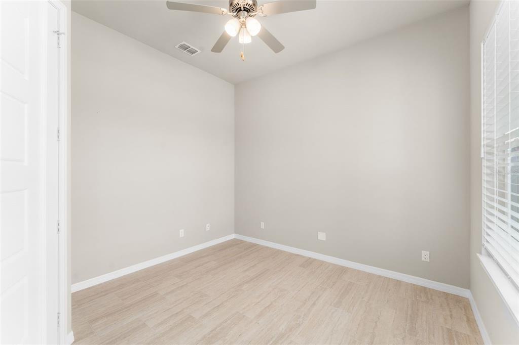 An empty room with light-colored walls, wood-look flooring, a ceiling fan, and a window — 6436 SW 77TH STREET, GAINESVILLE, FL