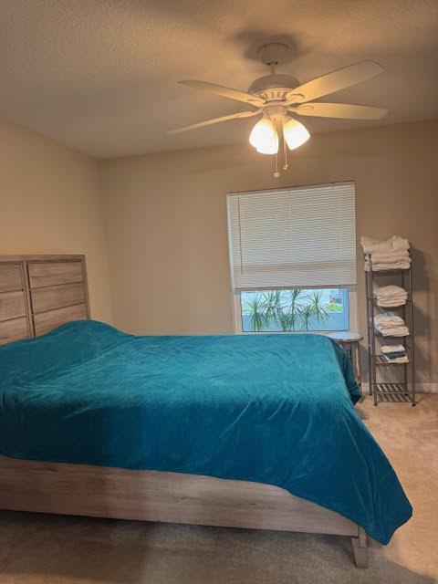 A bedroom features a wooden bed frame with a teal blanket, a ceiling fan, and blinds — 2130 88th Avenue, Vero Beach FL 32966, VERO BEACH, FL