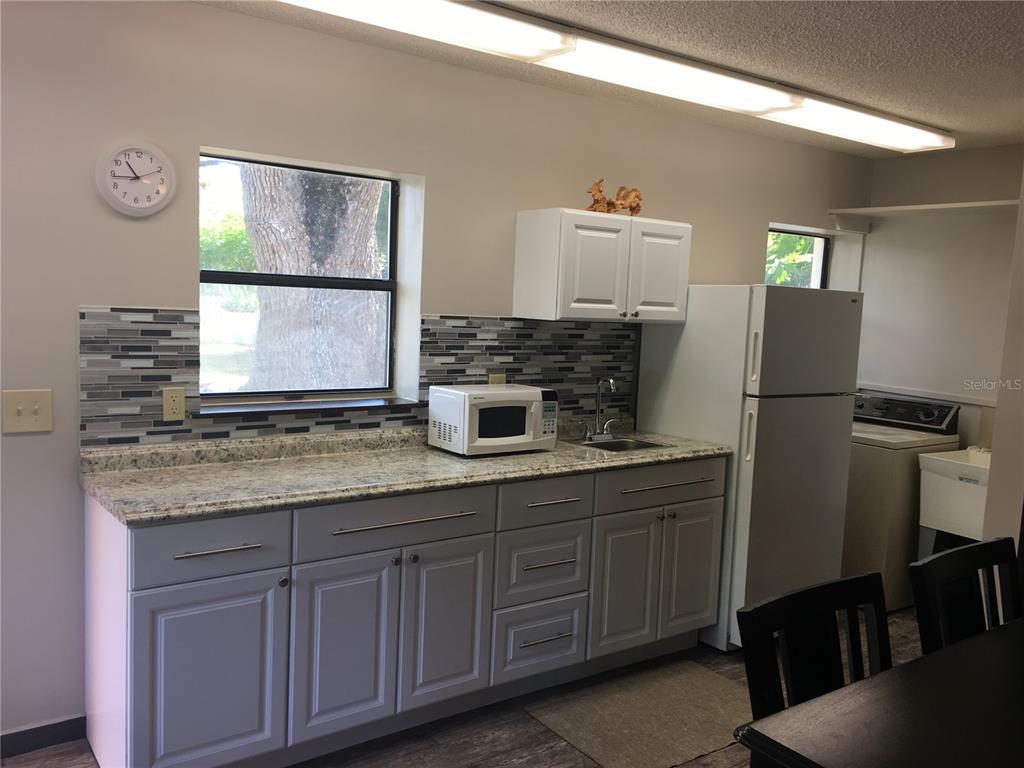 A kitchen features gray cabinets, granite countertops, a tiled backsplash, and a white refrigerator — 202 W PATTERSON STREET UNIT B, TAMPA, FL