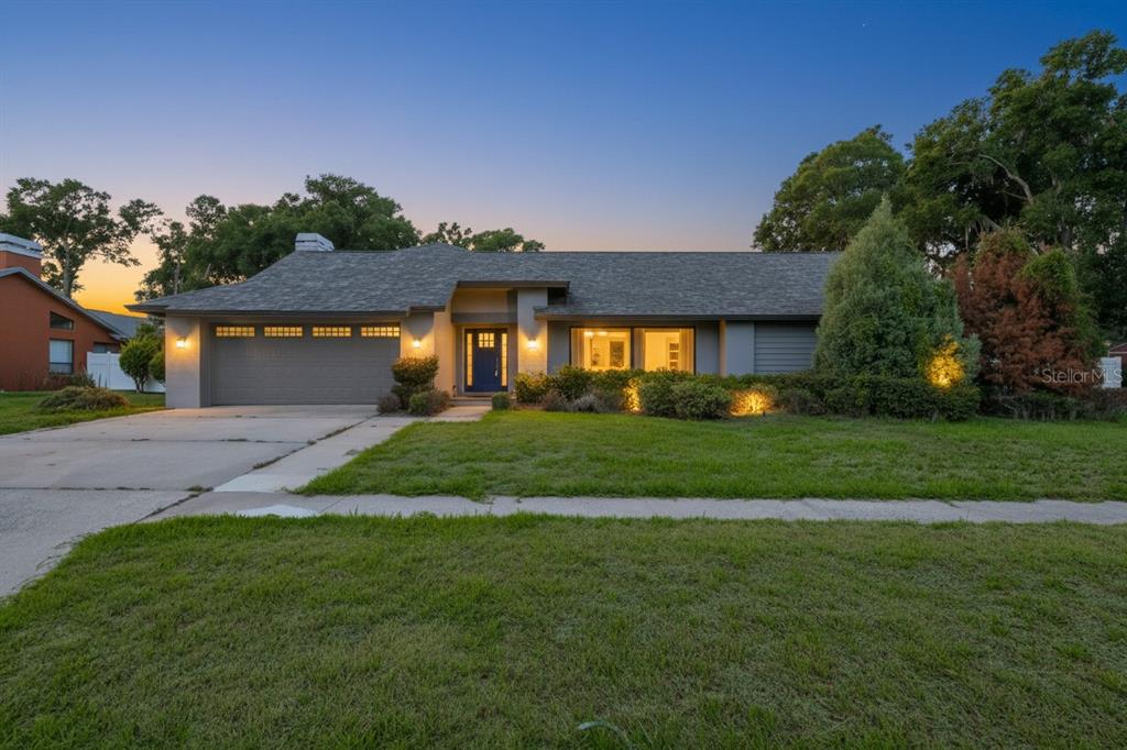 A single-story house with a gray garage, a blue front door, and a landscaped lawn — 2701 HERNDON STREET, VALRICO, FL