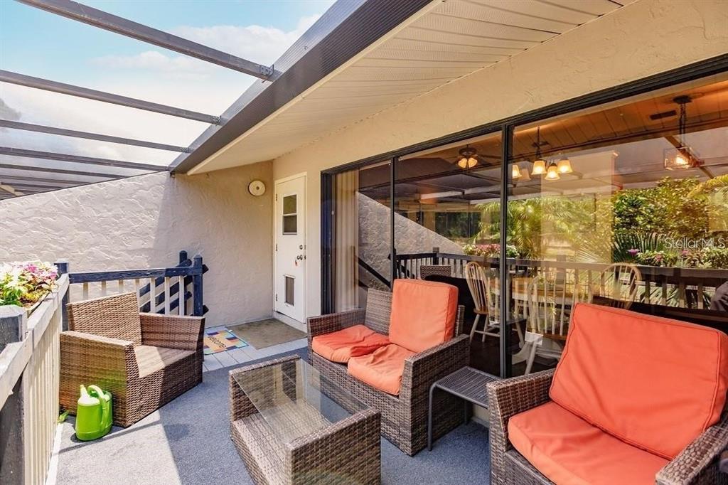 A covered outdoor patio features wicker furniture with orange cushions and a glass-topped table — 323 BOBBY JONES ROAD UNIT 323, SARASOTA, FL
