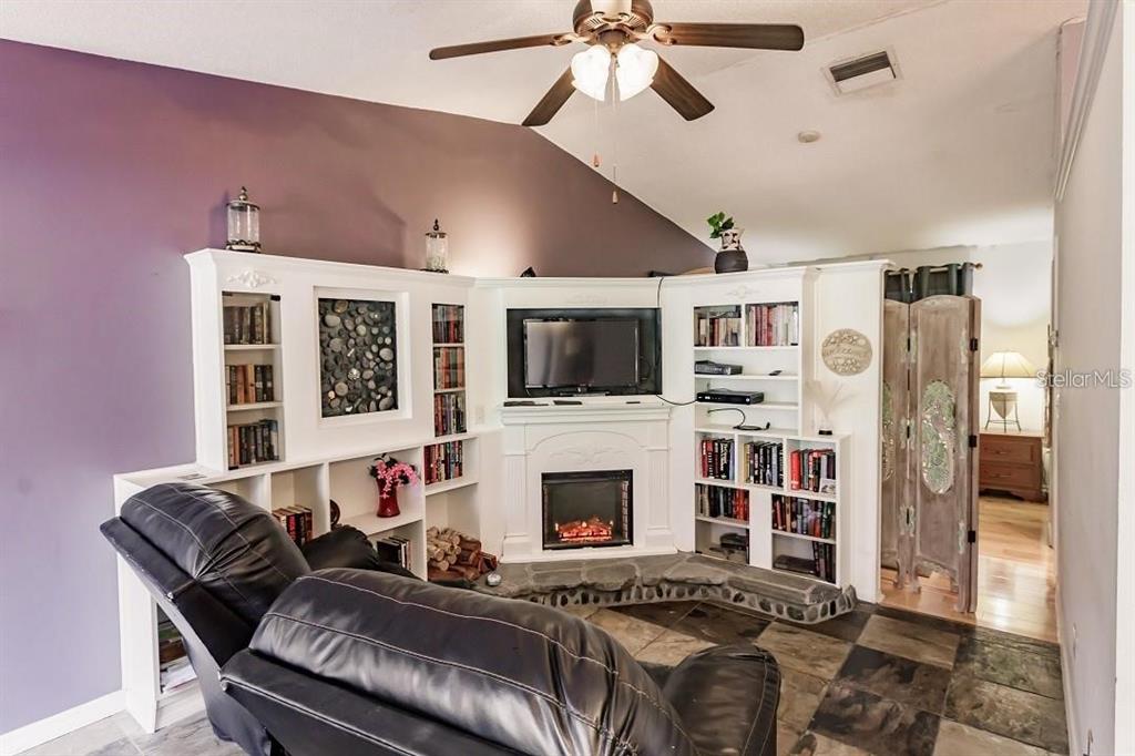 A living room features a corner fireplace, built-in shelving, a ceiling fan, and tile flooring — 323 BOBBY JONES ROAD UNIT 323, SARASOTA, FL