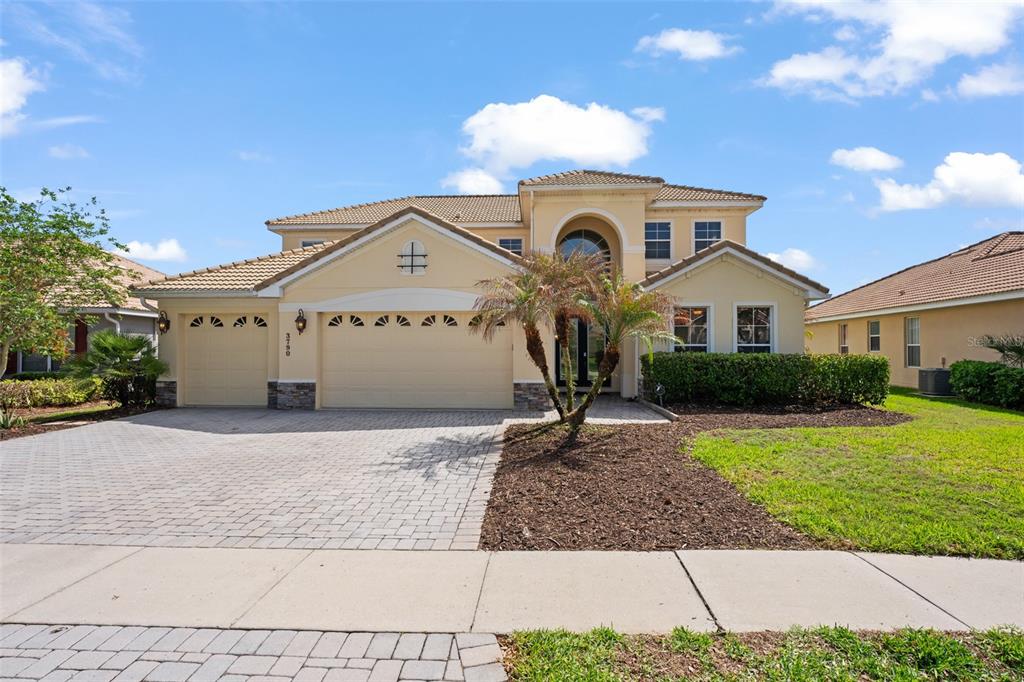 A two-story suburban house with a beige stucco exterior, tile roof, and a paved driveway — 3790 EAGLE ISLE CIRCLE, KISSIMMEE, FL