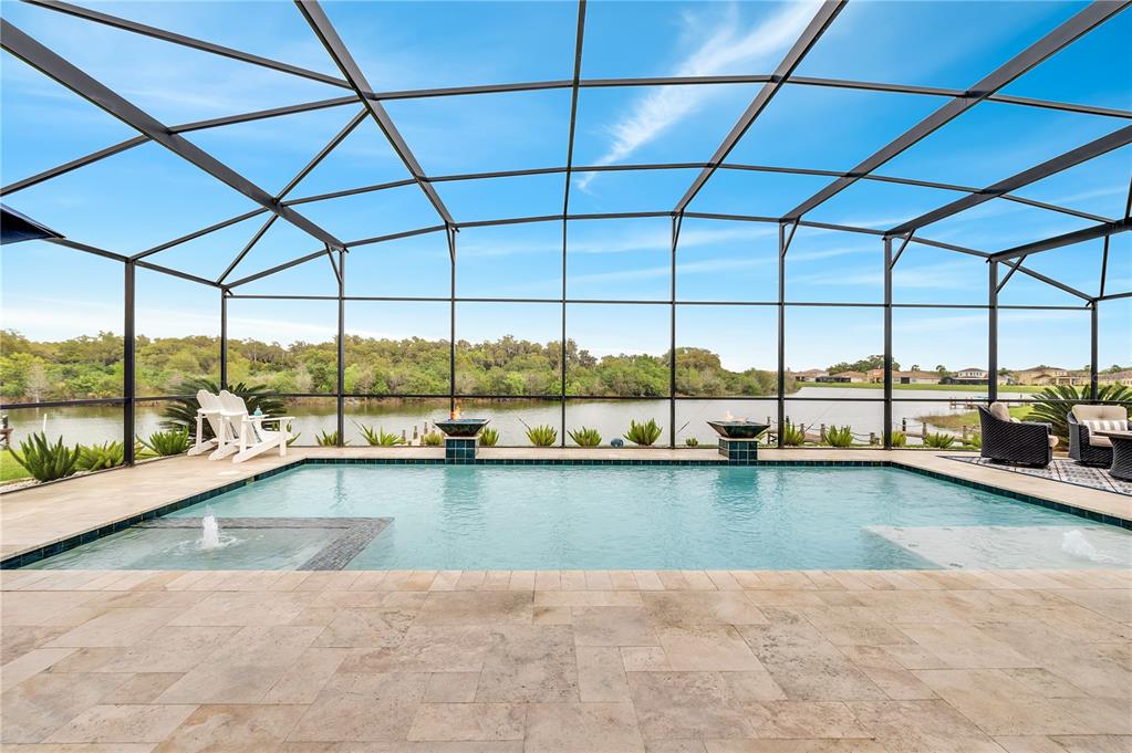 A screened-in pool patio features a swimming pool with fountains overlooking a lake — 3790 EAGLE ISLE CIRCLE, KISSIMMEE, FL