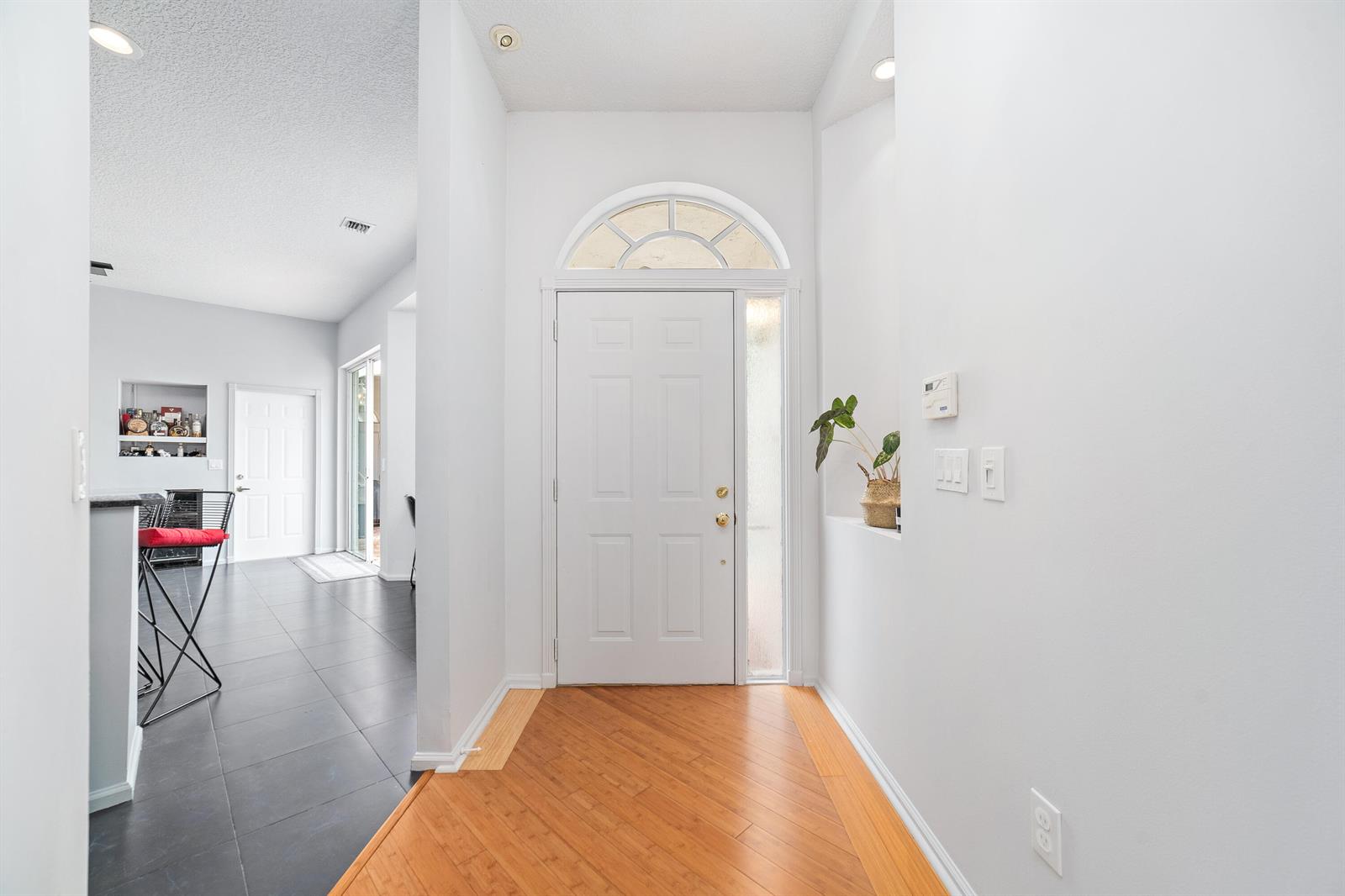 An entryway features a white front door, light wood flooring, and a tiled hallway — 2072 Chagall Circle, West Palm Beach FL 33409, WEST PALM BEACH, FL