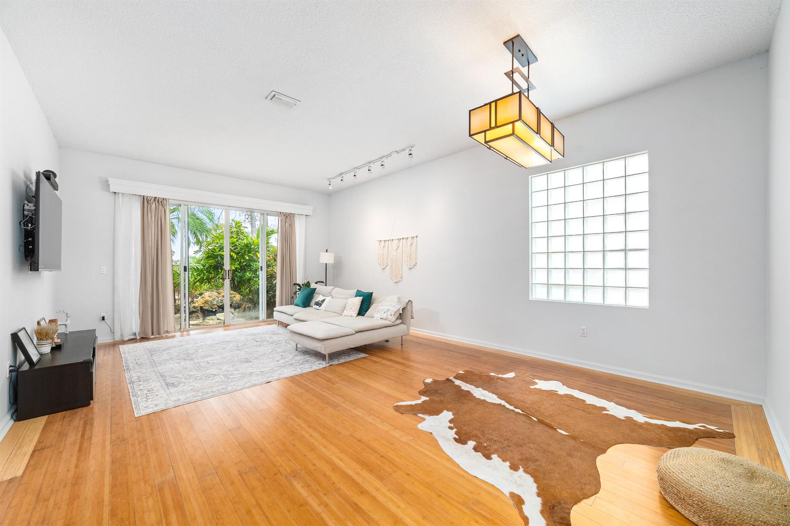 A living room with hardwood floors, a sectional sofa, a glass block window, and chandelier — 2072 Chagall Circle, West Palm Beach FL 33409, WEST PALM BEACH, FL
