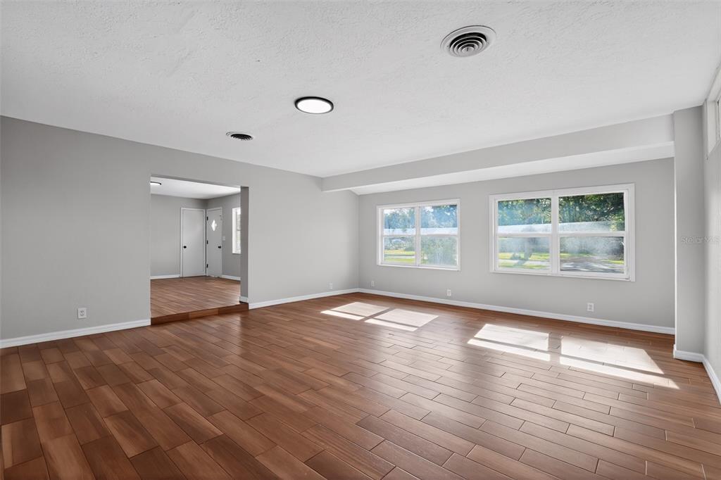 A spacious living room features light gray walls, wood-look flooring, and two large windows — 4600 NE 22ND AVENUE, OCALA, FL