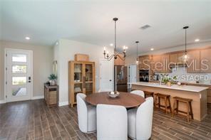 This open-concept kitchen and dining area features a wooden island, pendant lighting, and tile flooring — 88 SPRINGWOOD DRIVE, PALM COAST, FL