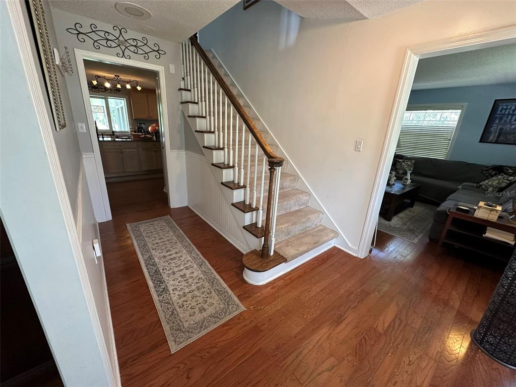 A foyer features hardwood floors, a carpeted staircase with a wooden railing, and arched doorways — 1105 S 9TH STREET, LEESBURG, FL