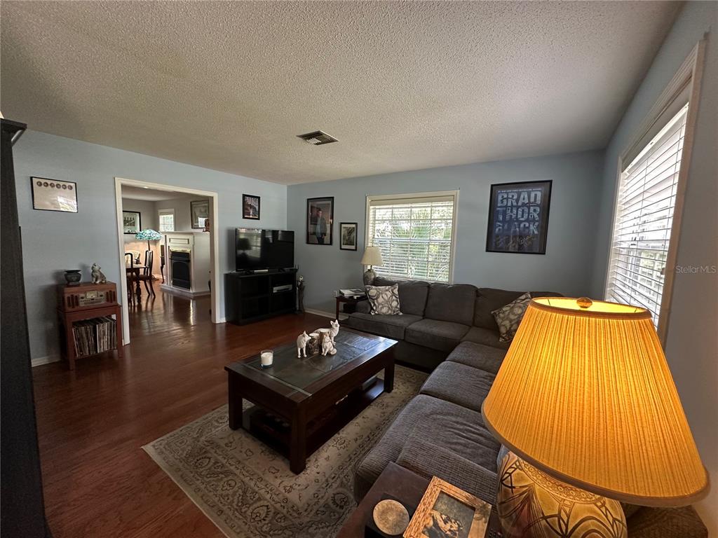 A living room features a sectional sofa, a coffee table, and a television on a stand — 1105 S 9TH STREET, LEESBURG, FL