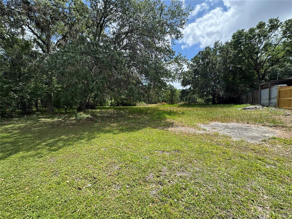 A grassy, partially shaded lot features a concrete slab and mature trees — 2424 CRYSTAL HILLS LOOP E, LAKELAND, FL