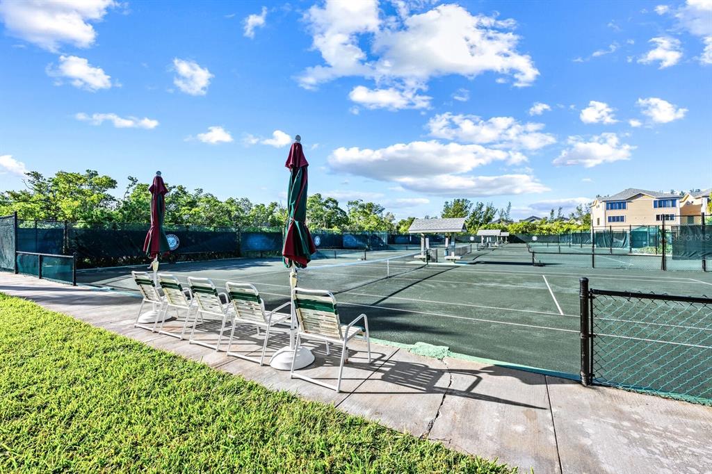 A row of chairs and umbrellas overlooks several outdoor tennis courts on a sunny day — 578 - 580 COMPANION WAY, LONGBOAT KEY, FL