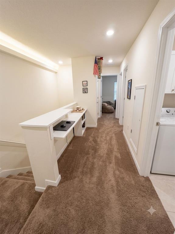 A carpeted hallway features a built-in desk overlooking a staircase and an adjacent laundry room — 9740 BROWN BURROW STREET, ORLANDO, FL