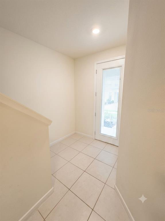 A tiled entryway features a white door with a glass panel and a staircase railing — 9740 BROWN BURROW STREET, ORLANDO, FL