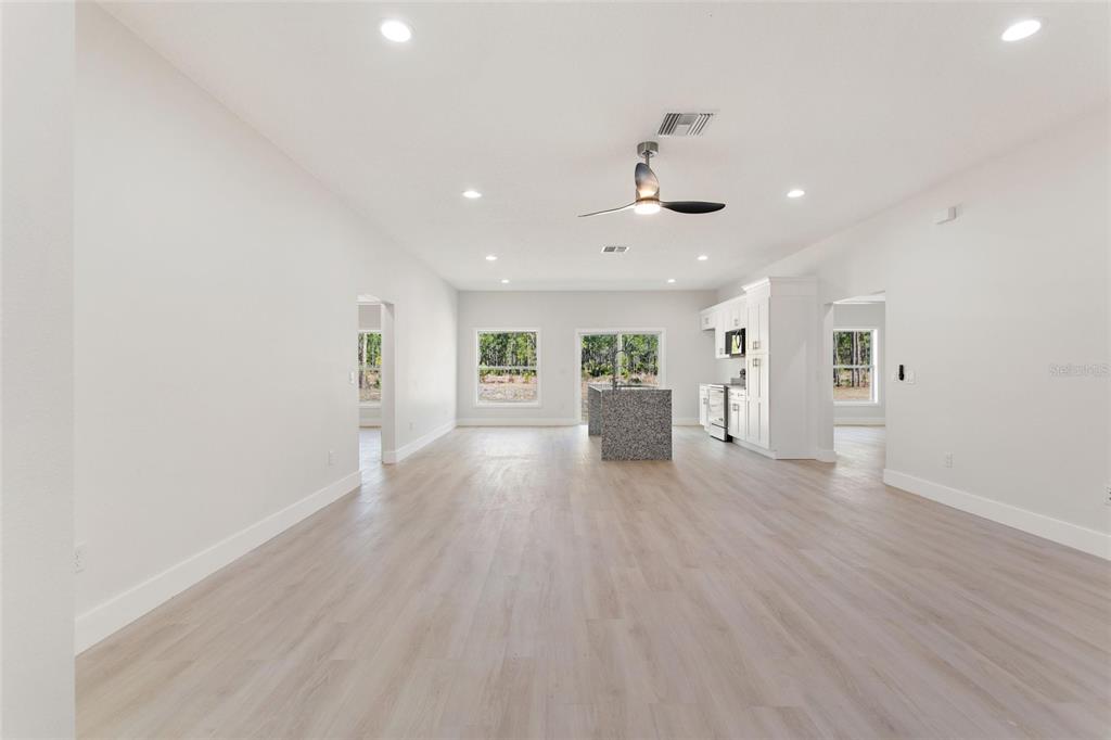 An open-concept living area features light wood flooring, a kitchen island, and white cabinetry — 3770 JAPONICA AVENUE, INDIAN LAKE ESTATES, FL