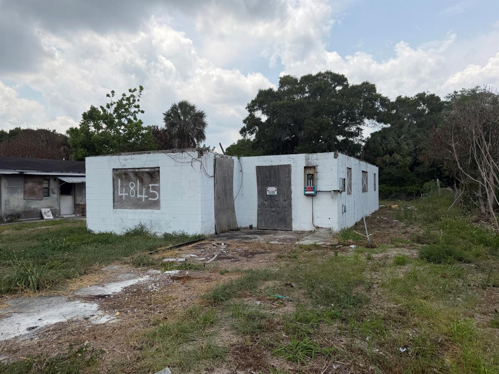 A dilapidated, single-story white concrete block building with boarded-up windows and doors — 4845 34th Avenue, Vero Beach FL 32967, VERO BEACH, FL