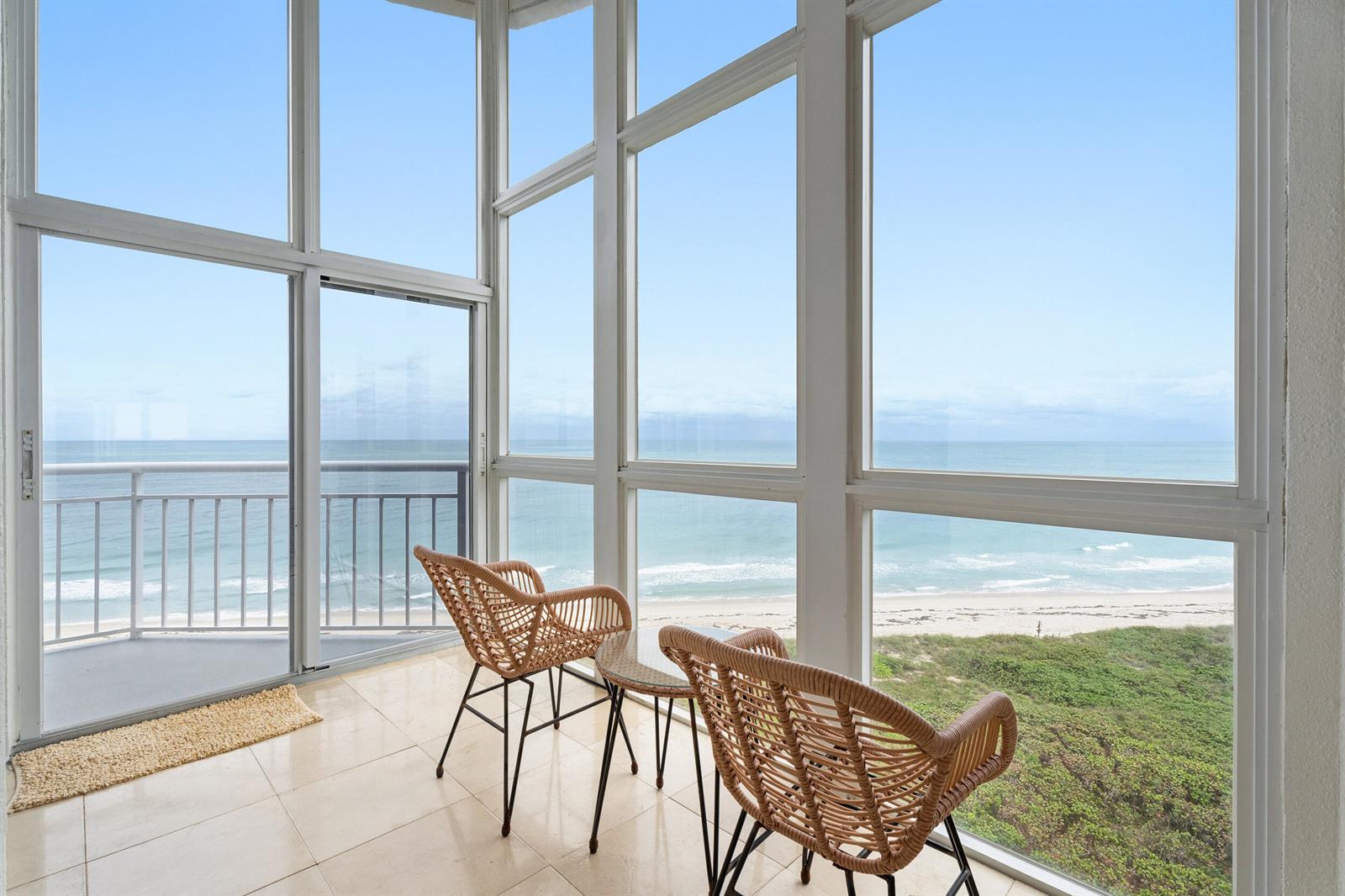 A sunroom with tile flooring and two wicker chairs overlooks the ocean and beach — 3870 N Highway A1a, Fort Pierce FL 34949, FORT PIERCE, FL