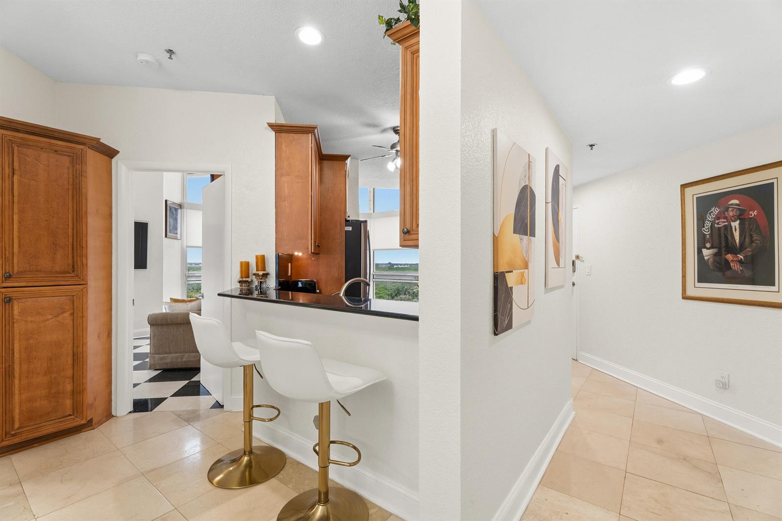 A kitchen pass-through with a black countertop and two white bar stools faces a hallway — 3870 N Highway A1a, Fort Pierce FL 34949, FORT PIERCE, FL