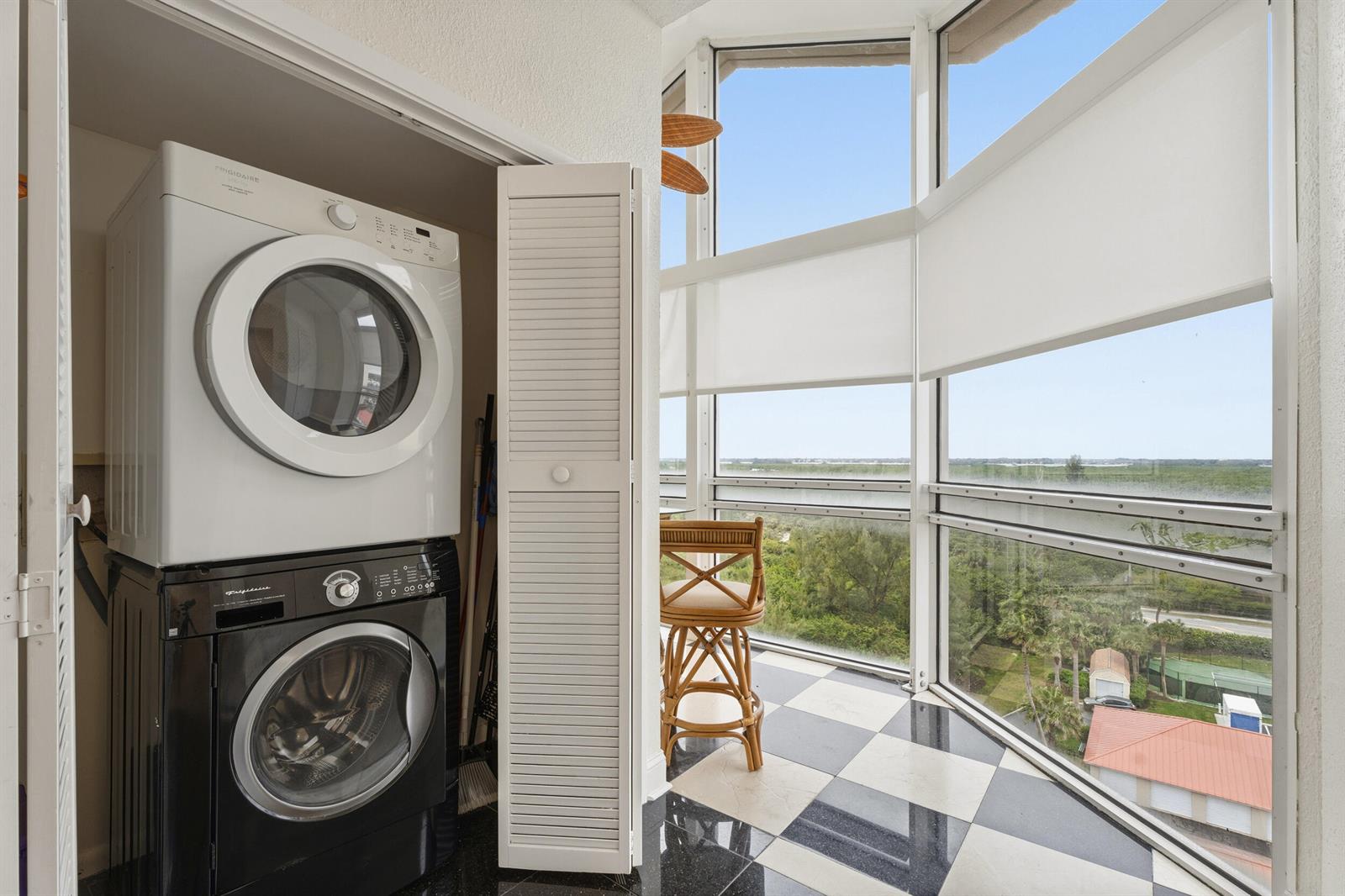 A stacked washer and dryer sit in a closet next to a sunroom with checkered flooring — 3870 N Highway A1a, Fort Pierce FL 34949, FORT PIERCE, FL