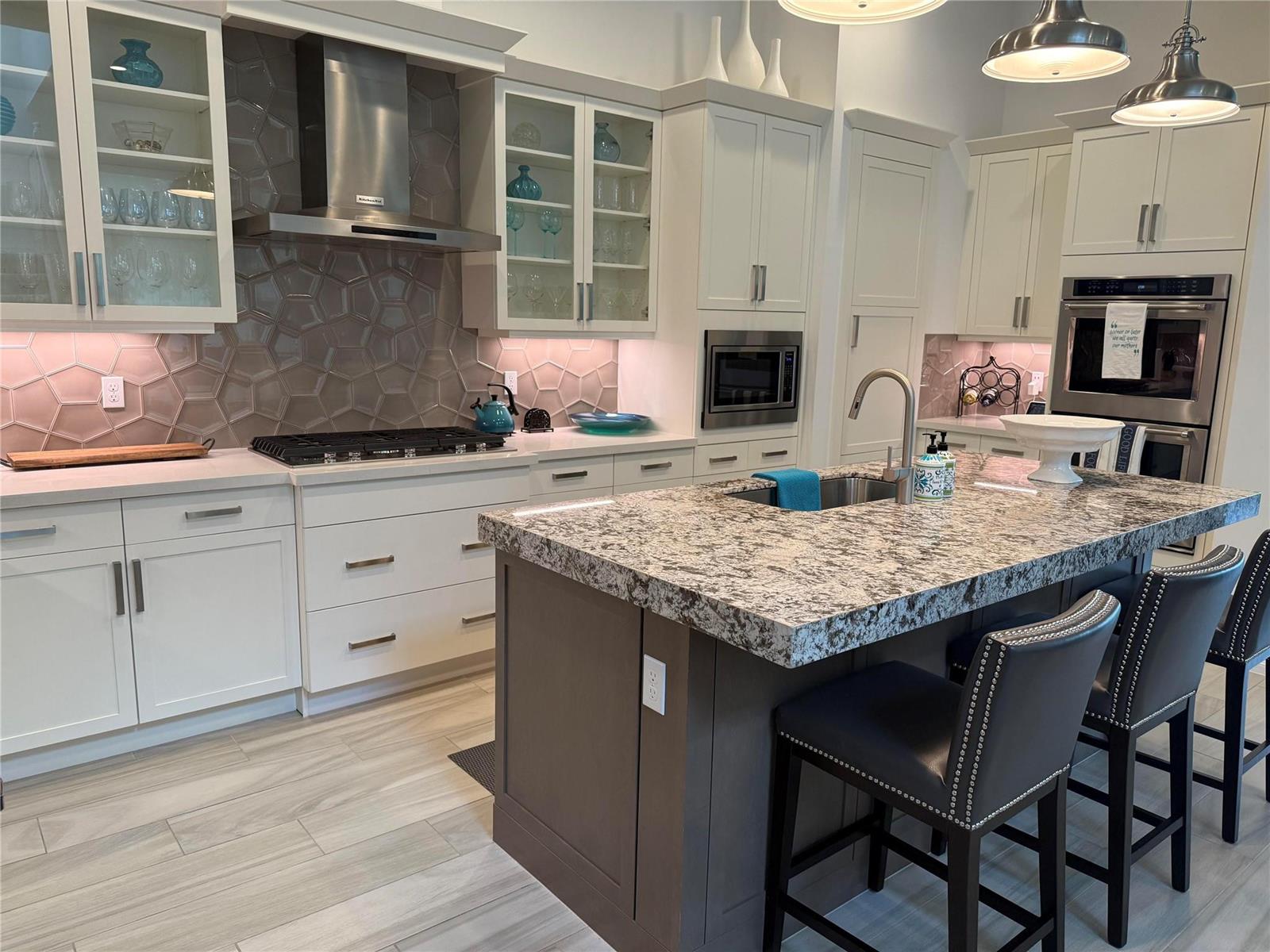 A modern kitchen features white cabinets, a granite-topped island, stainless steel appliances, and hexagon tile — 8467 Grand Prix Lane, Boynton Beach FL 33472, BOYNTON BEACH, FL