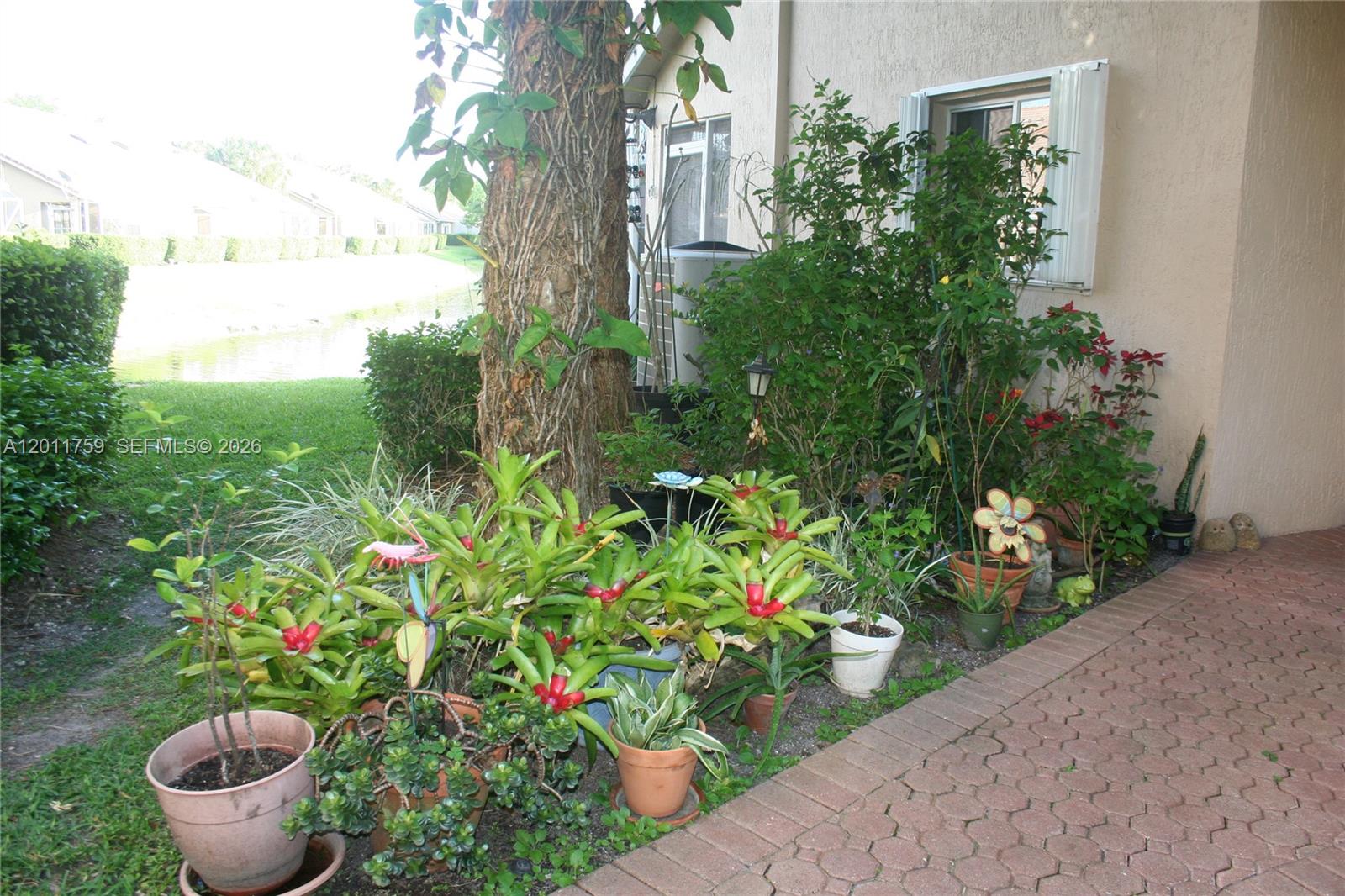 A patio area features a brick walkway, potted plants, and a large tree — 6200 NW 74th Ct, Parkland FL 33067, PARKLAND, FL