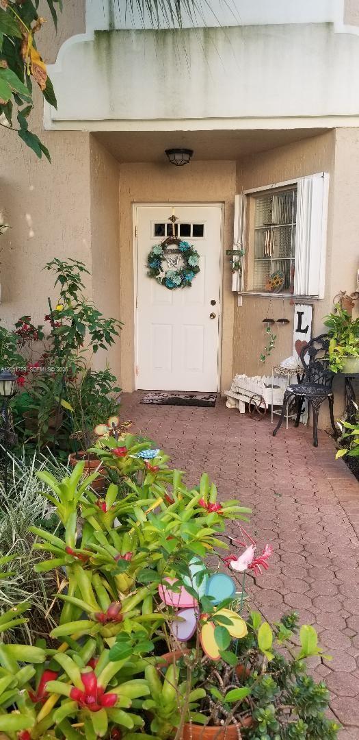 An exterior view of a front entryway featuring a white door, plants, and patio furniture — 6200 NW 74th Ct, Parkland FL 33067, PARKLAND, FL