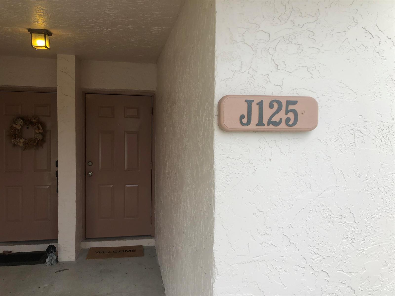 An exterior view of a building entrance with a door labeled J125 and a wreath — 3380 Jaywood Terrace # 1250, Boca Raton FL 33431, BOCA RATON, FL