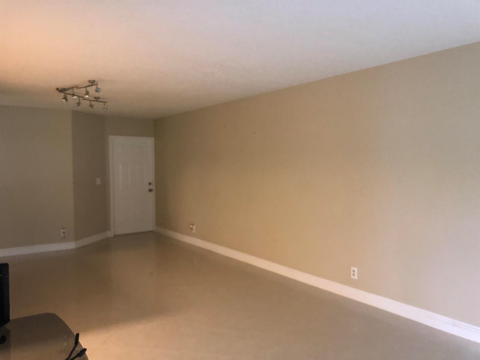 An empty room with beige walls, white trim, tile flooring, and a ceiling track light — 3380 Jaywood Terrace # 1250, Boca Raton FL 33431, BOCA RATON, FL