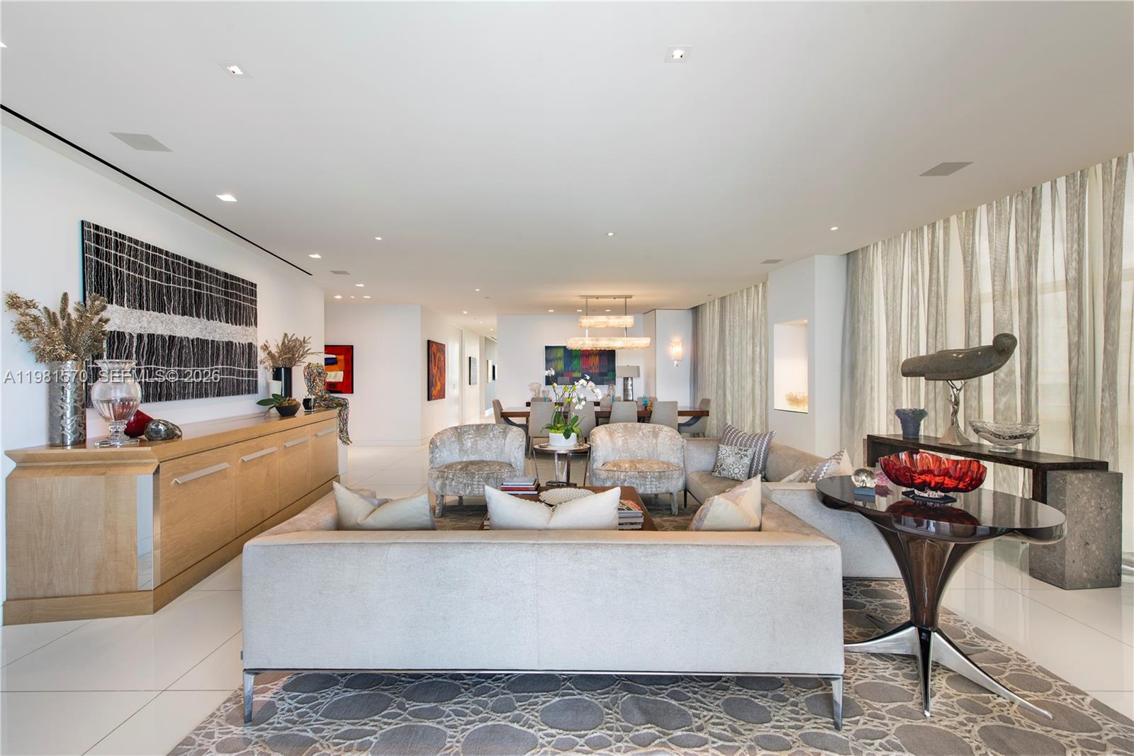 A modern living room features a neutral sofa, patterned rug, and a wooden sideboard — 9705 Collins Ave # 1702N, Bal Harbour FL 33154, BAL HARBOUR, FL