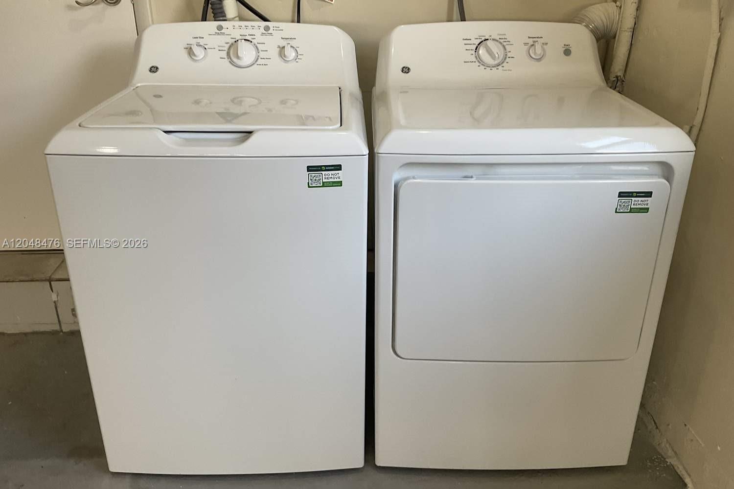 A white top-loading washing machine and a matching dryer sit side-by-side in a room — CUTLER BAY, FL