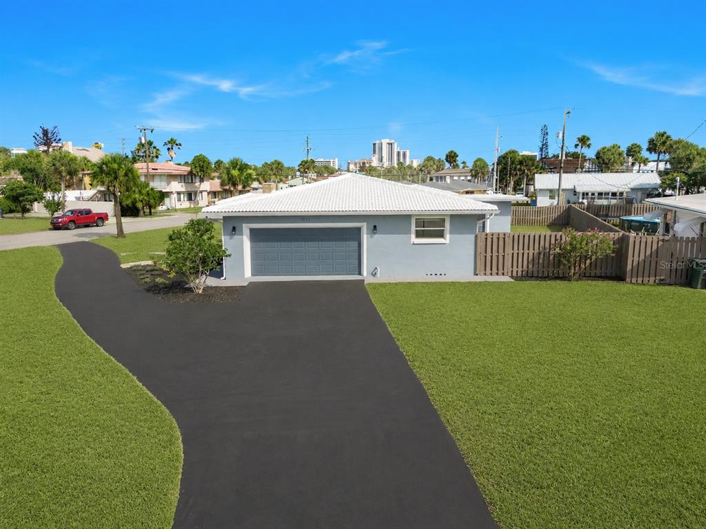 An exterior view of a light blue house with a white roof and paved driveway — 1032 BEL AIRE DRIVE, DAYTONA BEACH, FL