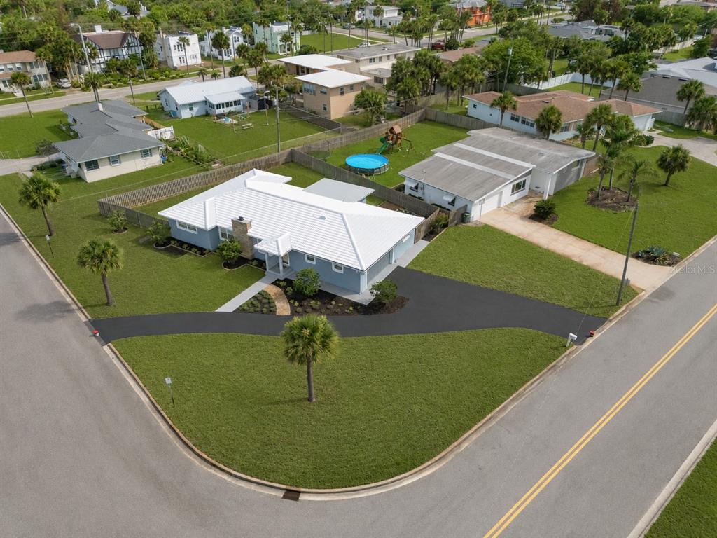 An aerial view shows a light blue house with a white roof and a curved driveway — 1032 BEL AIRE DRIVE, DAYTONA BEACH, FL